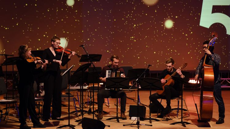 Fünf studentische Musiker*innen mit Geigen, Akkordeon, Gitarra und Kontrabass.